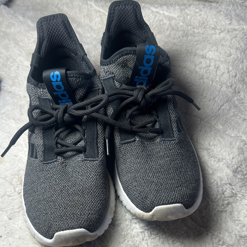 Adidas Clear foam gray and Black adidas sneakers with blue adidas lettering.